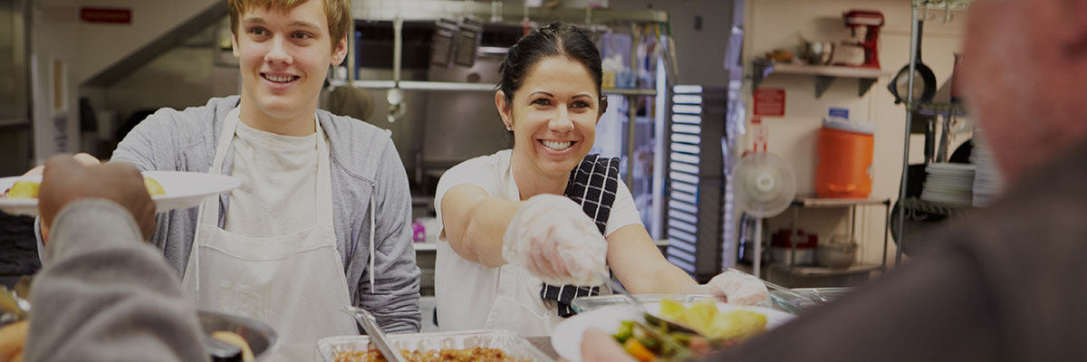 Volunteers serving hot meals in the Food & Care Coalition dining room